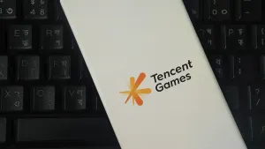 Tencent Games logo on a smartphone placed over a black keyboard