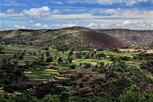 Terraced fields in a hilly landscape of the High Atlas Mountains under wide skies