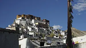 Thiksey mountain monastery with white walls and prayer flags under a cloudless sky