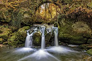 The three-armed Schiessentumpel waterfall in the Mullerthal in Luxembourg in sunny autumn weather as a long