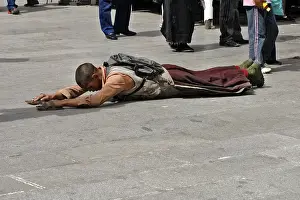 Tibetan pilgrim lies on the ground praying
