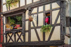 Timber-frame house decorated with vehicles in the historic old town of Riquewihr