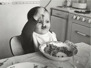 Toddler eats with spoon, between 50s and 60s
