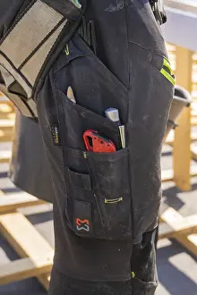 Tools in the pocket of a construction worker's black work trousers