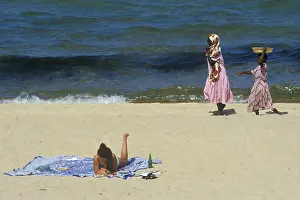 Tourist in bikini and traditionally dressed local woman at Kande Beach on Lake Malawi