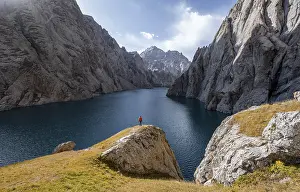 Tourist at the blue mountain lake between rocky steep mountain peaks