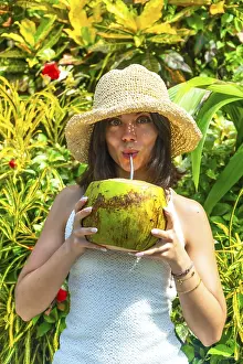 Tourist drinking coconut water in a lush tropical garden