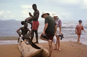 Tourists with local young men looking at a dugout tree on the beach of Lake Malawi, Malawi, Southern Africa, 1996, Africa