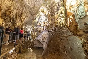 Tourists observing the magnificent stalactites and stalagmites formations inside postojna cave