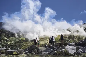 Tourists stand in front of the fumarole next to the former sulphur mine