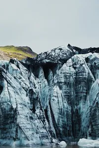 Towering blue glacier peaks with a hint of green vegetation above
