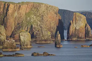 Towering cliffs and rocks in the sea under a clear sky