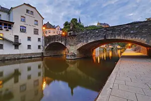 Town view of Vianden with the old stone bridge over the river Our and the castle in the evening
