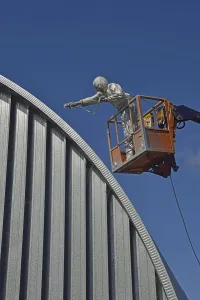 Tradesman spray painting the roof of an industrial building