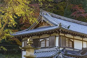 A traditional Japanese temple roof with stone lantern and colorful autumn leaves