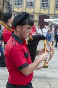 Traditional piper in band performing on city streets on May Day 2025