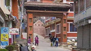 Traditional red brick gate with passers-by in a Nepalese city street