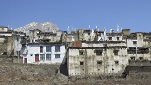 Traditional white-painted buildings in a mountain village with prayer flags against a clear sky