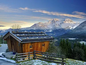 Traditional wooden hut, behind it the massif of the Hohen Goell in winter