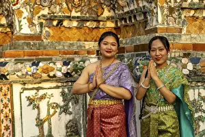 Traditionally dressed woman pose in front of the temple Wat Arun or Temple of Dawn in Bangkok