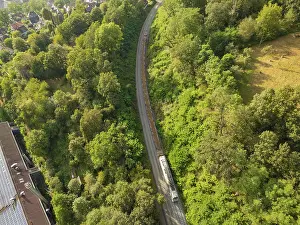Train on rails through a wooded landscape with neighbouring houses