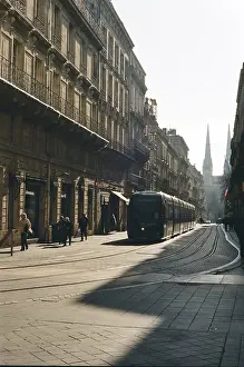 A tram on a city street surrounded by historic buildings in natural lighting