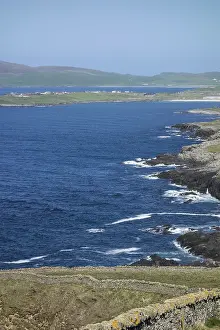 A tranquil coastline with villages and green hills in the distance