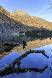A tranquil lake reflects the surrounding mountains and forests
