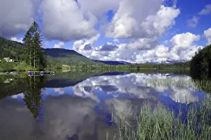Tranquillity of a mirror-smooth lake surrounded by mountains and cloudy skies