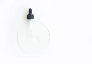Transparent serum dropper on white surface with clear liquid for skincare and beauty treatments