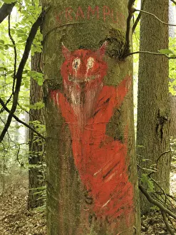 Tree trunk in the forest painted with red depiction of Krampus