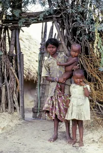 A tribal girl with her two sisters one standing nearby and another holding on her hip