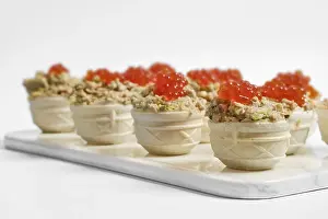 Tuna tartlets topped with bright red caviar on a white serving platter