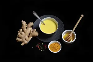 Turmeric milk in bowl, turmeric powder and ginger bulb