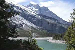 Turquoise alpine lake surrounded by coniferous forests and snow-capped peaks Oeschinen Lake