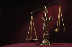 Empty unbalanced brass justice scales isolated on dark red background