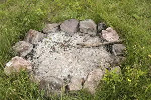Unlit camp fireplace with ashes and stones on mountain meadow