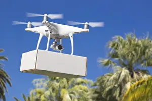 Unmanned aircraft system (UAV) quadcopter drone carrying blank package over tropical terrain