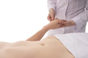 Unrecognizable crop masseuse massaging hands of faceless female customer relaxing in spa center on white background