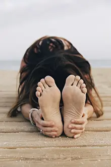 Unrecognizable woman practicing yoga on a beach