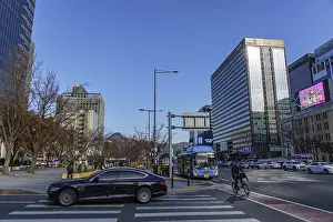 Urban scene with traffic on a street next to modern skyscrapers under blue sky