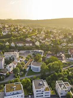 Urban settlement at sunset surrounded by green hilly landscape