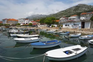 Various boats in a harbour surrounded by mountains and a quiet village panorama