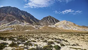 Vast desert-like landscape with volcanic rock and mountain range under a clear sky