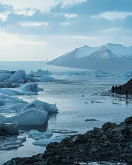 Vast glacier landscape with mountains and icebergs under a cloudy sky