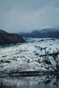 Vast glacier with rugged ice formations beneath a cloudy sky