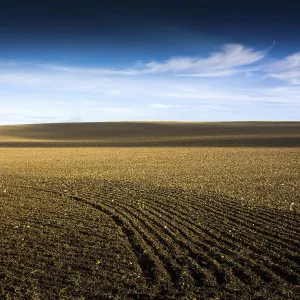 A vast stretch of farmland showcases freshly tilled soil stretching towards the horizon