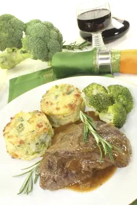 Venison medallions with potato gratin and rosemary against a light background