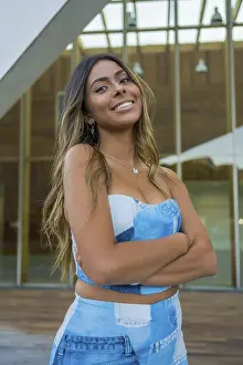 Vertical photo of a pretty woman in denim clothes standing with arm crossed smiling at camera