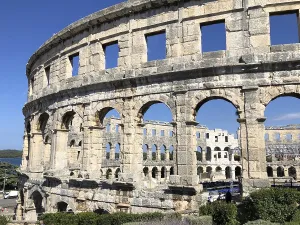 View of an ancient amphitheatre with stone arches under a blue sky